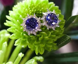 Pair of earrings with blue gemstones on a green flower